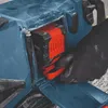 A gloved hand is inserting a battery into a blue power tool. Produktbild-Vorschau