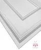 A close-up, angled view of white decorative wall panels with a textured surface and raised borders, set against a white background. A small logo is visible in the bottom right corner. Produktbild-Vorschau