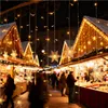 A Christmas market at night, with stalls decorated with lights and snowflake ornaments. Voir les images du produit