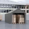 A grey tent garage filled with cardboard boxes on pallets, with a larger building in the background. Náhled obrázku produktu