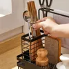 A hand is shown reaching for a fork and spoon from a kitchen sink organizer. The organizer holds various kitchen utensils and cleaning tools. Voir les images du produit