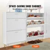 A white shoe cabinet with gold accents, featuring multiple flip-down drawers filled with shoes. The cabinet is placed on a rug in what appears to be an entryway or living room. Náhľad obrázku produktu