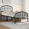 A black metal twin bed with a decorative headboard and footboard, neatly made with bedding, is shown in a bedroom setting with a rug and a bedside table with a lamp. Produktbild-Vorschau