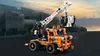 A LEGO Technic mobile elevated work platform toy is shown in front of a blurred cityscape background. Anteprima dell’immagine prodotto