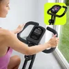 A woman is using an exercise bike indoors, with a view of a garden through a window. Anteprima dell’immagine prodotto
