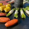 A close-up shot of food items being cooked on a flat-top grill. Produktbild-Vorschau