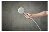A hand holding a shower head against a tiled wall. Produktbild-Vorschau