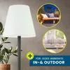 A floor lamp with a white shade is shown in front of a gray wall. Two circular insets show the lamp used in an outdoor patio setting and an indoor living room setting. Text indicates it is suitable for indoor and outdoor use. Anteprima dell’immagine prodotto