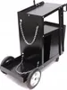 A black metal welding cart with two large wheels at the front and two smaller wheels at the back. It has a tray at the front and a larger compartment in the middle. Chains are attached to the front tray and to the side of the main body. Produktbild-Vorschau