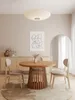 A dining room scene with a round wooden table and chairs, a sideboard, and artwork on the wall. Produktbild-Vorschau