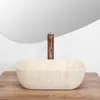 A beige basin with a copper faucet sits on a wooden surface in front of a large mirror. Podgląd zdjęcia produktu