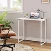 A home office setup with a white folding desk, a laptop, a desk lamp, and a brown office chair. Produktbild-Vorschau