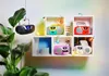 Several colorful boomboxes are displayed on white shelves, some with decorative light bulbs and plants. Produktbild-Vorschau