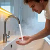 A man washing his hands under a modern kitchen faucet in a bathroom. Produktbild-Vorschau