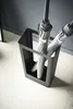 A modern, minimalist umbrella stand holding two folded umbrellas. Produktbild-Vorschau