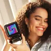 A young woman is smiling and holding a small, black electronic device with a colorful pixelated screen. Náhled obrázku produktu
