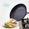 A frying pan is tilted over a plate with toast and avocado, with a fried egg sliding out of the pan. Produktbild-Vorschau