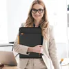 A woman in a business suit holds a laptop bag in an office setting. Náhled obrázku produktu