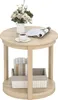 A round, two-tiered side table with a vase of flowers, a cup of coffee, and a magazine on the top surface, and books and a storage basket on the lower shelf. Podgląd zdjęcia produktu