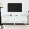 A white TV cabinet with two doors on each side, mounted on thin legs, is shown against a white wall. A black flat-screen TV is mounted on the wall above the cabinet. Two decorative vases and a book are placed on top of the cabinet. A floor lamp is to the l Produktbild-Vorschau