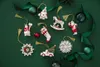 A collection of Christmas ornaments arranged on a green surface, with green ribbons and baubles. Podgląd zdjęcia produktu