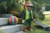 A large Playmobil figure dressed as a gardener stands next to a colorful ball and a skateboard on a sunny day in a garden. Náhľad obrázku produktu