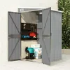 An open grey metal shed with tools and storage inside, placed outdoors on a paved surface next to a wall and greenery. Náhled obrázku produktu
