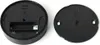 The image shows the back of a round, black remote control with its battery cover removed, revealing a battery compartment. The battery cover is shown separately next to it. Produktbild-Vorschau