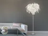 A modern living room with a white sofa, glass coffee table, and a decorative floor lamp. Produktbild-Vorschau