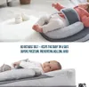 A baby is shown lying on a gray baby sleep positioner with an adjustable belt. The image is split into two parts, with text overlay describing the product's features. Produktbild-Vorschau