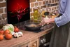 A person is cooking in a kitchen with a backsplash featuring red chili peppers. Náhled obrázku produktu