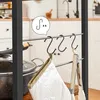 A close-up view of a kitchen shelf with S-hooks holding kitchen utensils and oven mitts. Produktbild-Vorschau
