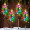 Four solar-powered cypress tree lights with colorful LEDs are displayed in a snowy outdoor setting, suggesting a festive holiday decoration. Anteprima dell’immagine prodotto