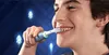 A young person is shown smiling while using an electric toothbrush. Blue arrows pointing upwards are visible in the background, suggesting upward movement or improvement. Produktbild-Vorschau