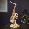 A wooden model of a saxophone on a stand, placed on a book. Náhľad obrázku produktu