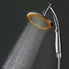 A close-up shot of a shower head with water spraying from it against a dark background. Produktbild-Vorschau