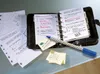 A desk with an open planner, loose papers, sticky notes, and a pen. Podgląd zdjęcia produktu