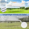 A white pop-up tent is shown in two different outdoor settings: one sunny with a green lawn and lake, and another rainy with water droplets on the tent fabric. Produktbild-Vorschau