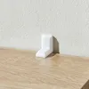 A white corner protector is placed on a wooden shelf against a textured white wall. Náhľad obrázku produktu