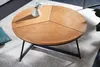A round wooden coffee table with a black metal frame, placed on a rug in a living room setting. A small vase with a plant is on the table. Produktbild-Vorschau