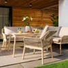 An outdoor patio set with a sofa, chairs, and a dining table, set on a patio with a wooden wall backdrop. Náhľad obrázku produktu