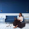 A woman is sitting on a foldable mattress in a living room, using a laptop. Anteprima dell’immagine prodotto