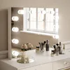 A vanity mirror with lights and makeup accessories on a dresser. Produktbild-Vorschau