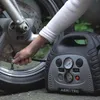 A person is using a portable air compressor to inflate a motorcycle tire. Podgląd zdjęcia produktu