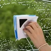 Weiß-blauer magnetischer Fensterreiniger, von einer Hand gehalten, reinigt ein seifiges Fenster mit grünem Außenhintergrund Náhľad obrázku produktu
