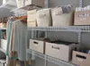 A closet with shelves holding various storage bins, boxes, and clothing items. Produktbild-Vorschau