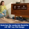 A woman is demonstrating how a vacuum cleaner can reach under furniture. Produktbild-Vorschau