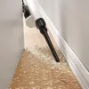 A cordless vacuum cleaner is shown cleaning up debris on a wooden floor next to a wall and baseboard. Produktbild-Vorschau