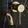 Close-up of a gold-colored faucet handle and spout against a black marble background. Podgląd zdjęcia produktu