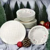A Christmas-themed tablescape with plates, bowls, miniature Christmas trees, pinecones, and ornaments. Podgląd zdjęcia produktu